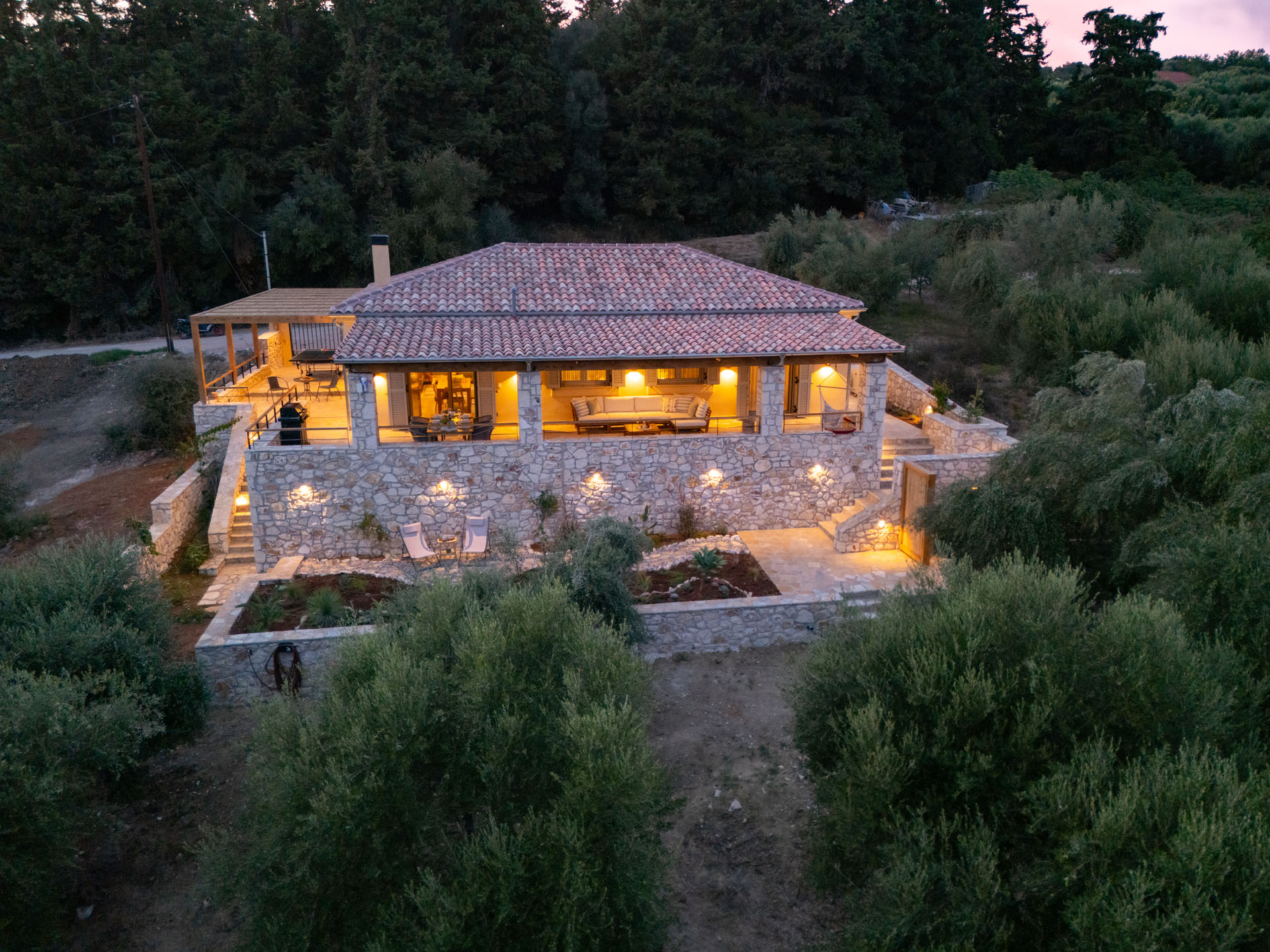 The house lit at dusk among olive trees